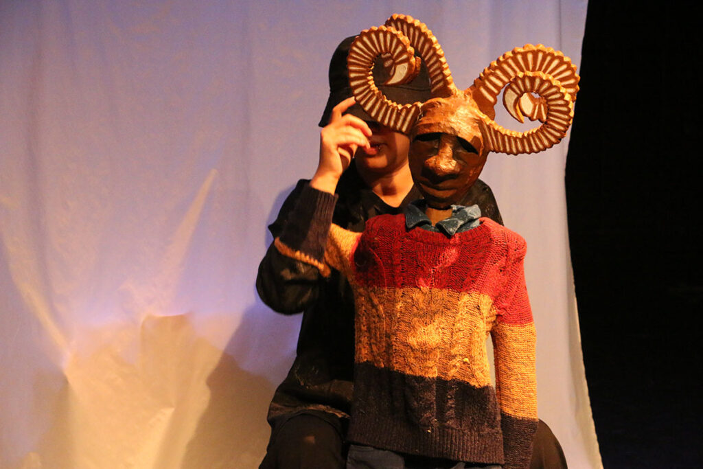 Puppet with horns and a sweater in front of woman